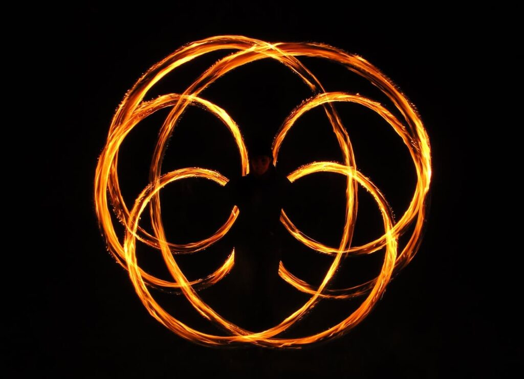 action shot of fire performer spinning fire poi in a dark setting