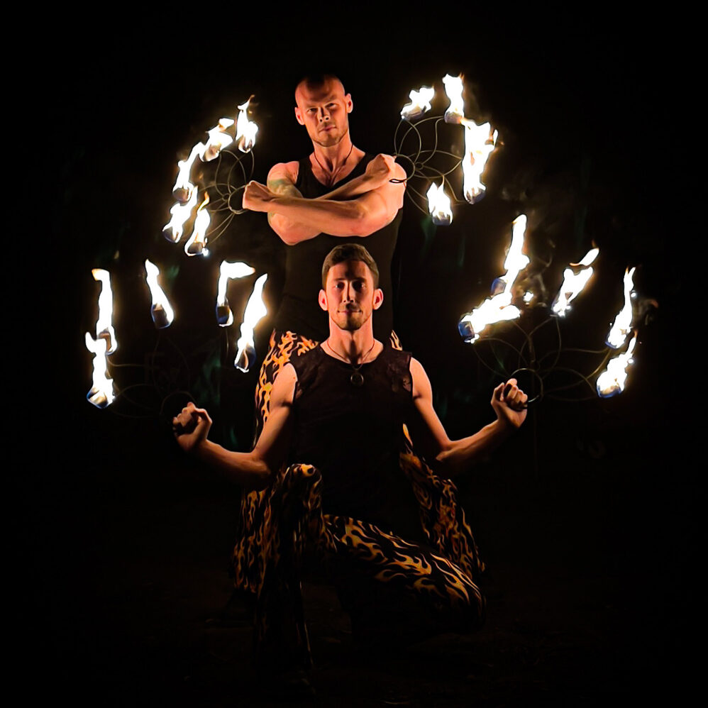action shot of fire performers holding two pairs of fire fans with russian grips