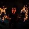 action shot of fire performer with fire dance fans