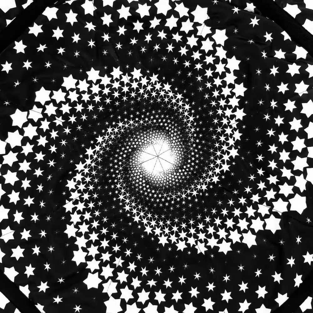 close up shot of flow star with white spiral star design on black background