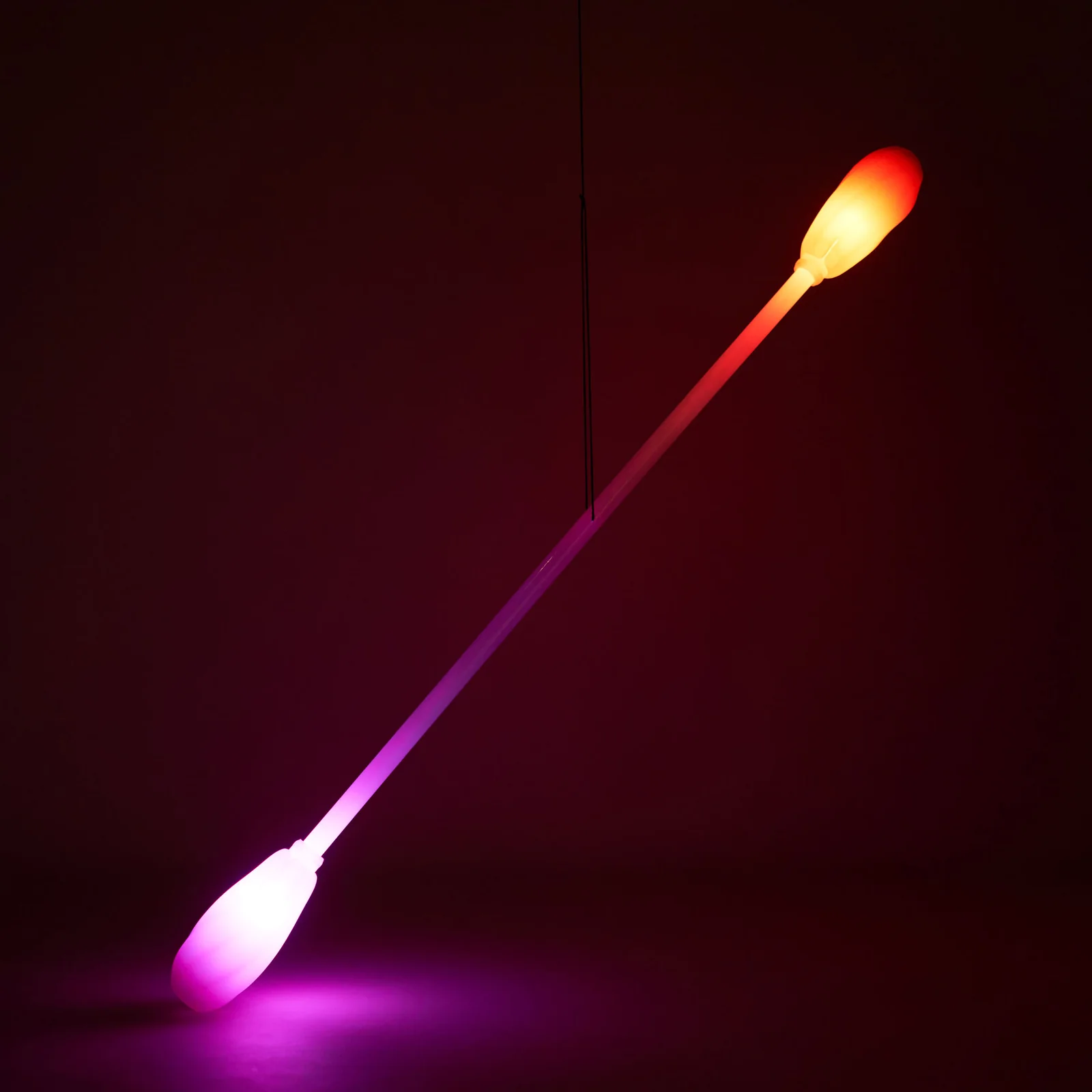 Leviwand being held up by it's string in a dark room